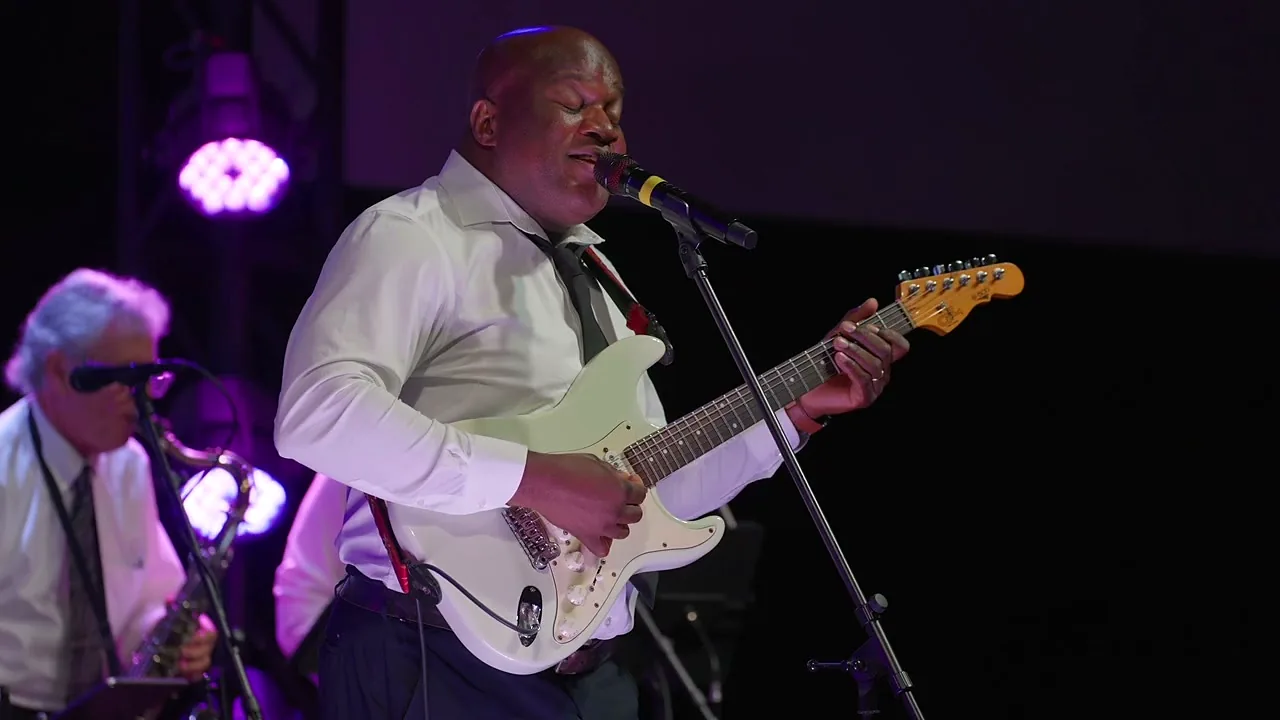 Lead vocalist singing and playing guitar during a live set
